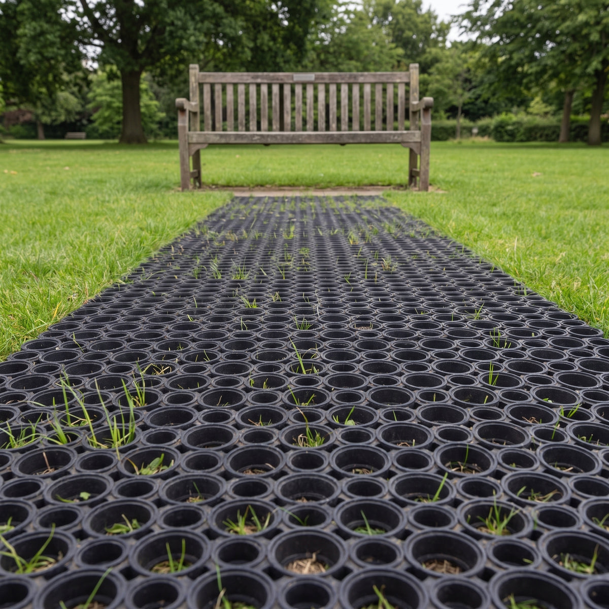 Rubber grass mats forming a continuous path across a park lawn to a bench