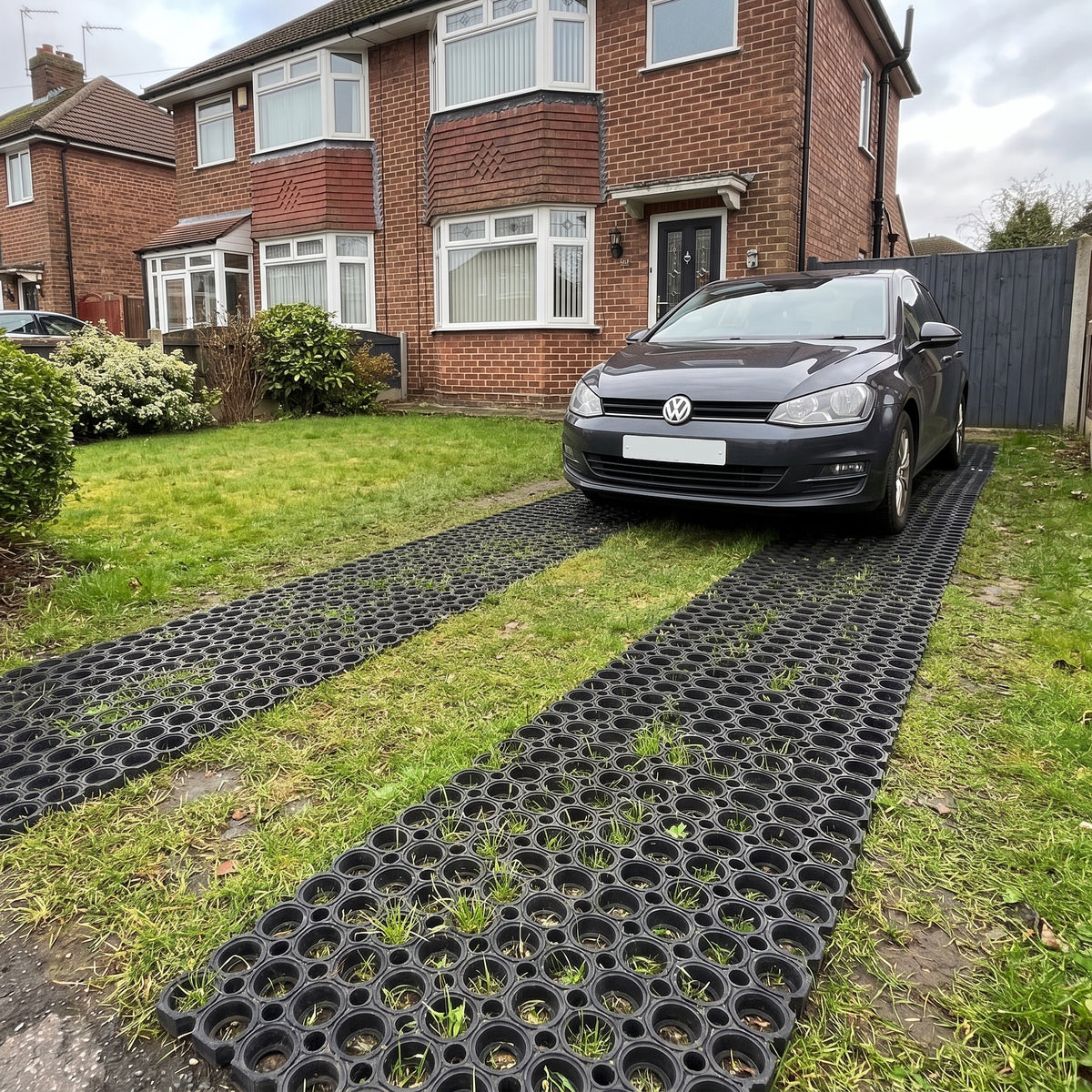 Rubber grass mats laid as wheel tracks on a front lawn used as a grass driveway