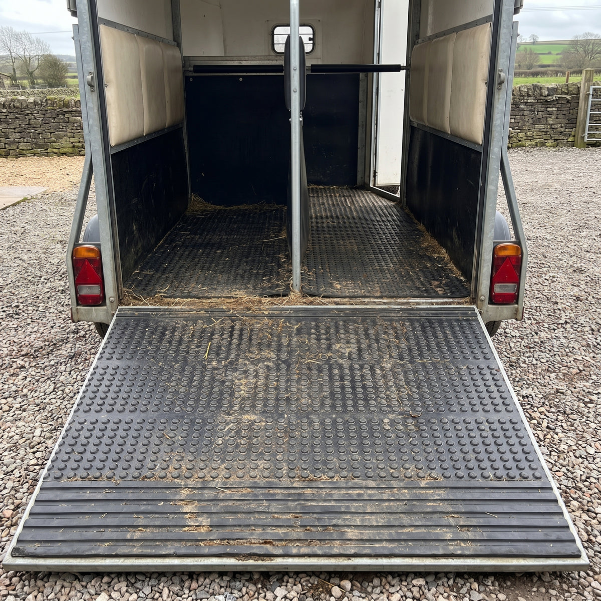 Black bubble-top rubber stable mats cut to fit the floor and ramp of a two-horse trailer