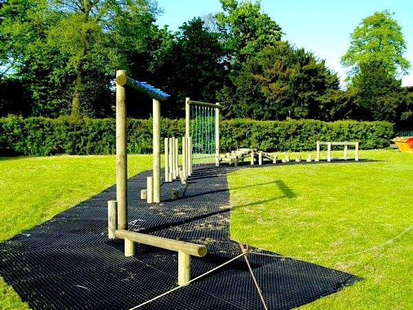 Rubber grass mats laid under a wooden trim trail in a park
