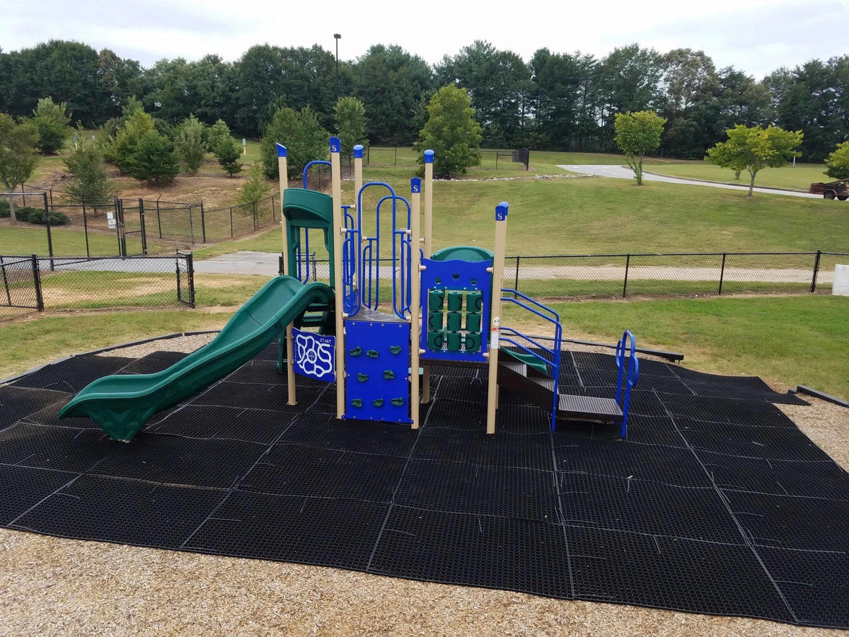Rubber grass mats tied together as impact surfacing under a playground climbing frame and slide